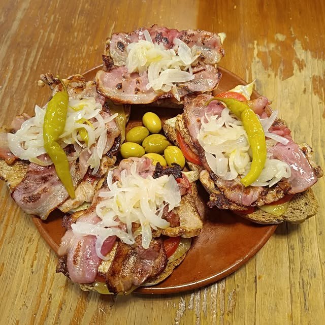 Fuente de montaditos de panceta a la plancha con cebolla, guindillas y aceitunas